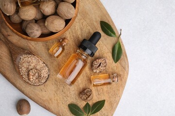 Nutmeg essential oil, nuts and leaves on light table, top view