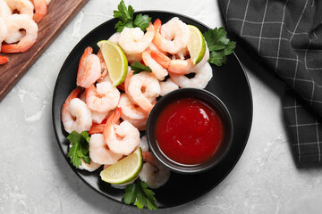 Tasty boiled shrimps with cocktail sauce, parsley and lime on light grey table, flat lay