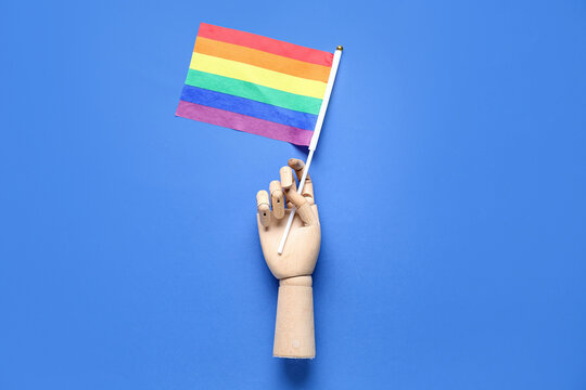 Wooden hand with LGBT flag on blue background