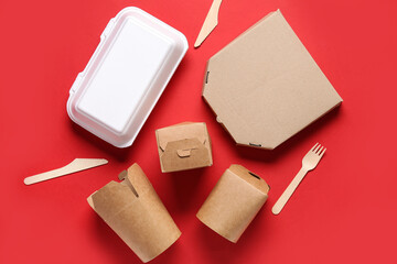 Different takeaway paper containers and cutlery on red background