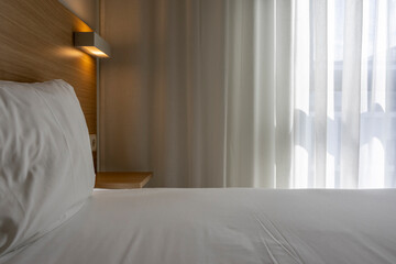 White pillow on bed with light lamp in hotel bedroom, interior minimal design