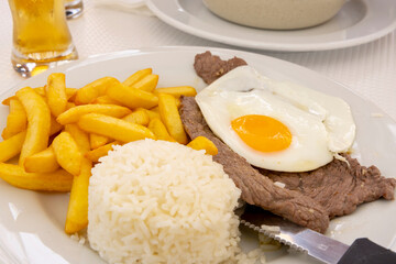 Rice with fried egg and beef on a plate in a restaurant. "Prego no Prato" a typical Portuguese dish.