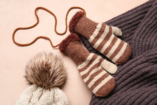 Winter mittens with warm hat and scarf on beige background
