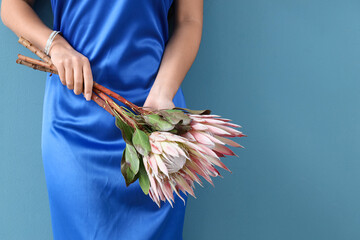 Young woman with beautiful protea flowers on blue background, closeup
