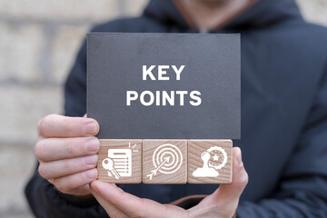 Man holding wooden cubes with icons and black sticky note with inscription: KEY POINTS. Key points...