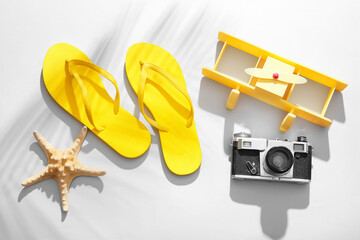 Composition with vintage photo camera, flip-flops and toy plane on light background