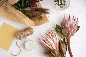 Composition with beautiful pink protea flowers, threads, envelope and candle on white background