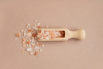 Wooden scoop with Himalayan pink salt on brown background