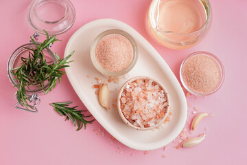 Bowls with Himalayan pink salt and garlic on pink background