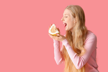 Young woman with pomelo slice on pink background