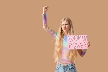 Young girl holding paper with text WOMAN POWER on beige background