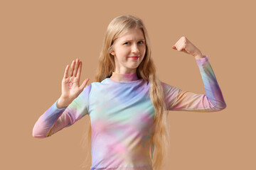 Young woman with drawn gender symbol showing muscles on beige background