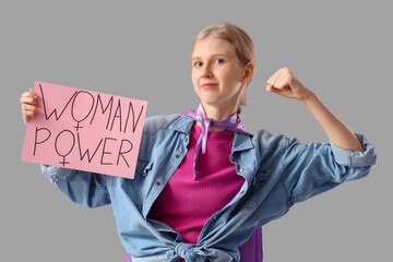 Young girl holding paper with text WOMAN POWER on light background