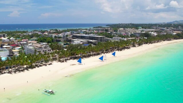 Crystal clear waters meet pristine white sands at the tropical paradise of Boracay's beach, surrounded by lush greenery. Slow Motion Camera 4K RAW. 