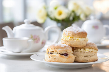 Traditional English cream teas, scones with clotted or whipped cream on the white table, white cafe background, with tea and teapot on the back