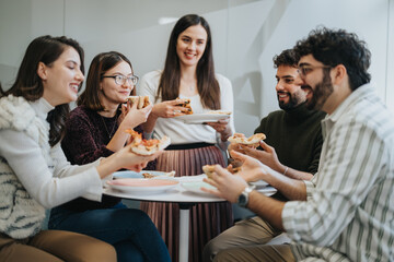 Multicultural business team enjoying lunch break together, discussing and eating pizza. Successful...
