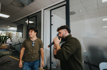 Male employees having fun at work with a microphone, talking to their colleagues.