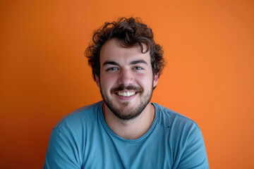 Fototapeta premium A man with a beard is smiling in front of an orange wall