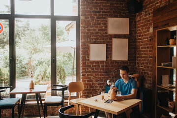 A caucasian student enjoying free time alone at a coffee bar, browsing and messaging on a smart phone, creating a positive and relaxed atmosphere.
