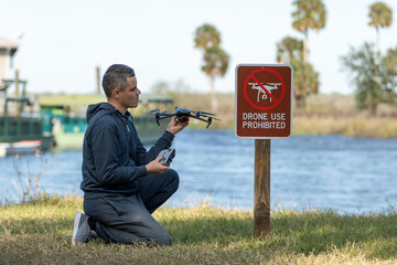 Operator is disappointed because he can not fly his quadcopter in national park no drone area. Man is unable to use his UAV near restriction notice sign