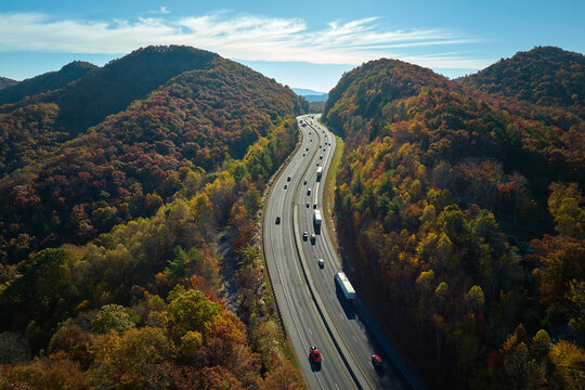 View from above of I-40 freeway in North Carolina heading to Asheville through Appalachian mountains in golden fall season with fast driving trucks and cars. Interstate transportation concept
