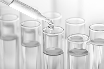 Laboratory analysis. Dripping liquid from pipette into glass test tube on blurred background,...
