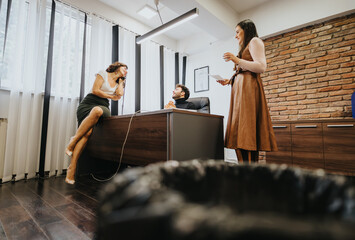 Casual business meeting with two women and a man in a modern office, expressing dynamic teamwork and communication.