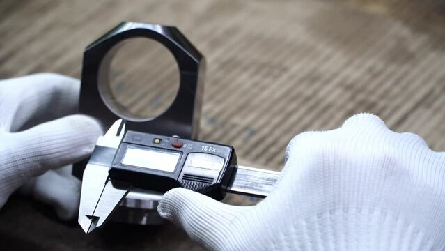 Work at the Heavy Industry Manufacturing Facility concept,technician measures metal parts by hand using a digital vernier caliper in a heavy product.