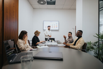 Diverse partners in a modern office strategize for business growth, analyzing statistics and sharing ideas towards success.