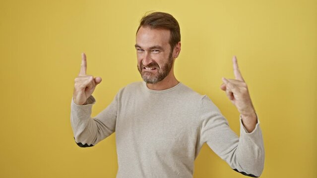 Crazy-fun hispanic rock star lets loose, heavy metal expression - gesturing rock symbol with hands on isolated yellow background.