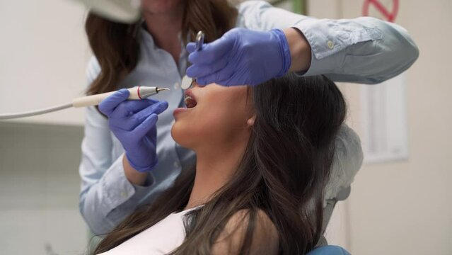 Side view beautiful young woman with dental braces sitting in chair, having dental procedure  