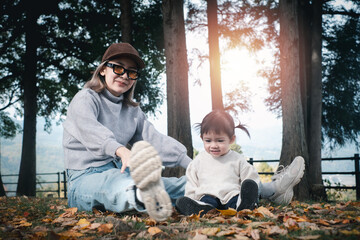 young asian mother and daughter enjoying nature having a good time life with joy outdoors in the park. Happy fanimy spending time together in the garden autumn season.