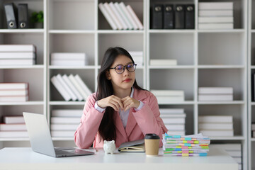 Asian woman in the office working in finance and accounting. Piggy bank and money saving concept.