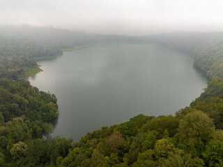 Tamblingan Lake encompassed by dense forest, in fog and clouds, Bali, Indonesia