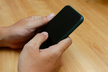 hand holding smartphone over wooden background
