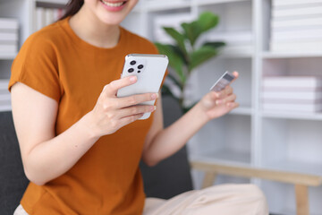 Happy young asian woman using credit card and mobile phone shopping online. Online payment via credit card.