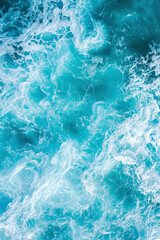 Fototapeta na wymiar Vertical aerial view from above of turquoise ocean water with splashes and foam for abstract natural background and texture.