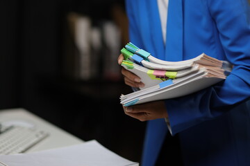 Businesswoman hands working in Stacks of paper files for searching and checking unfinished document achieves on folders papers at busy work desk office. - obrazy, fototapety, plakaty