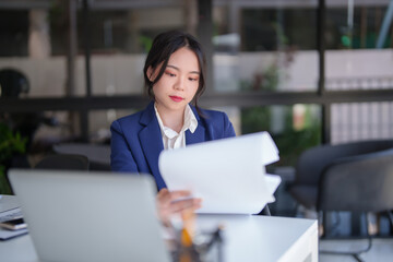 Businesswomen reading finance chart document of new business to analysis strategy investment and management about new startup project while working about finance report on digital laptop in workplace