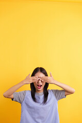 Young women open mouth and covering eyes with both hands on isolated yellow background