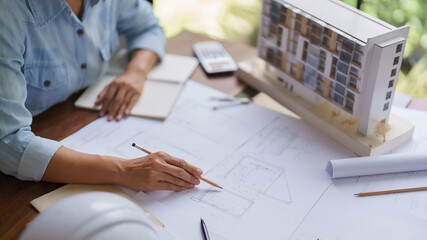 Architect woman work to drawing building project on blueprint about construction architectural plan
