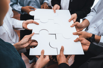 Diverse corporate officer workers collaborate in office, connecting puzzle pieces to represent...