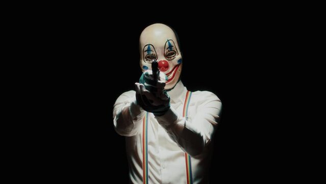 Man with scary clown mask on his face and He points a gun at the camera