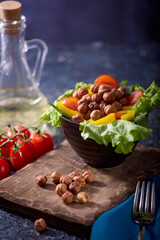 On a wooden board there is a bowl with a salad of fresh vegetables and hazelnuts. Vitamin breakfast, lunch or dinner for health and healthy nutrition
