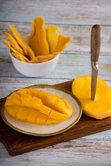 Close-up on a plate of sliced juicy pulp of tropical sweet mango. Healthy fruit snack of ripe mango...
