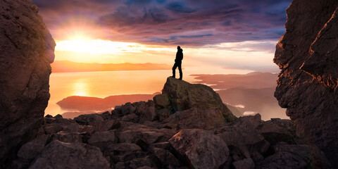 Adventure Man on top of Rocky Mountain Cliff. Mountain landscape from BC in Background. 3D