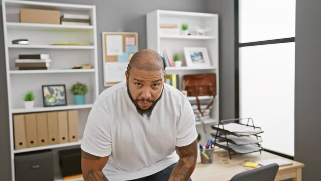 Portrait of a confident african american man with tattoos standing with crossed arms in a modern office setting.