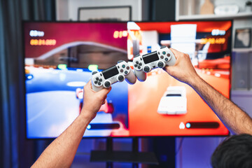 Close up photo of holding joystick crashing or cheerful friends on car racing competition of video game on blurred screen. Concept of lifestyles gamer on weekend with friend in living room. Sellable. © InfiniteFlow