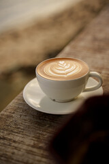A white clean cup of hot latte coffee on handmade wooden table, vintage look
