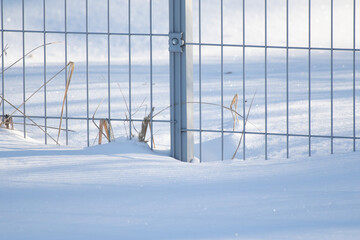 The metal fence is covered with snow in the winter.